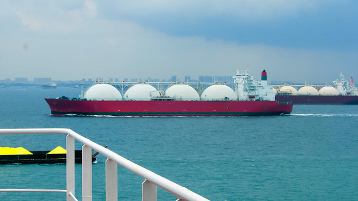 Large liquefied natural gas tanker with spherical storage tanks sailing across water